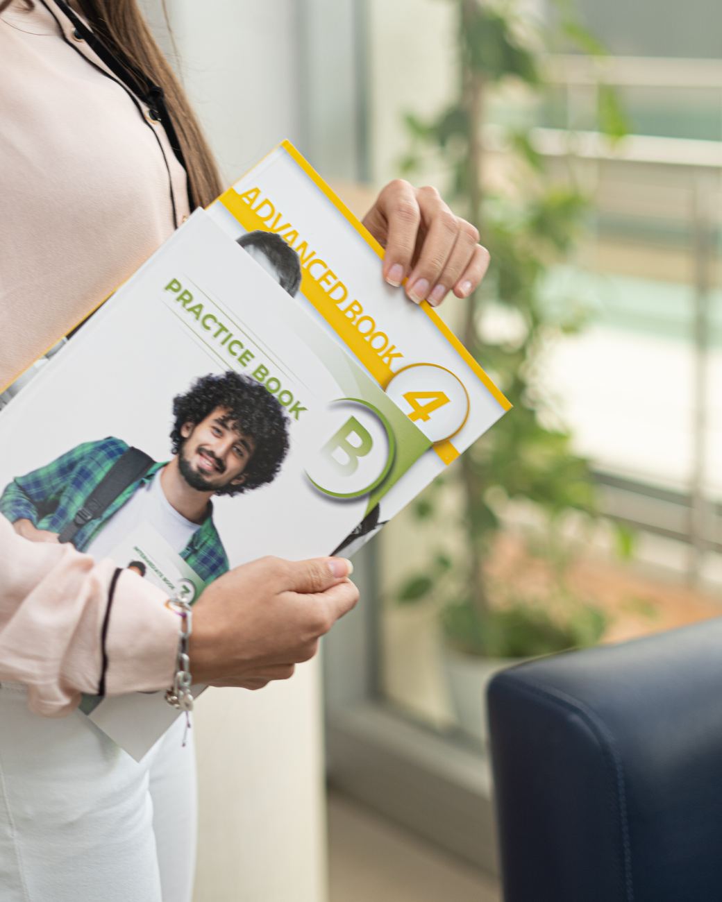Estudiante de Intenpro sosteniendo los libros Practice Book y Advanced Book